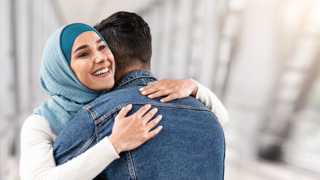 Happy Reunion. Joyful Muslim Woman In Hijab Hugging Her Husband At Airport